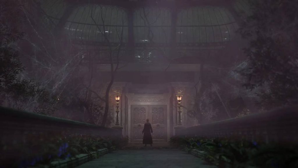 the player character from Hogwarts Legacy standing in a vast greenhouse covered in vines and trees before a large door 