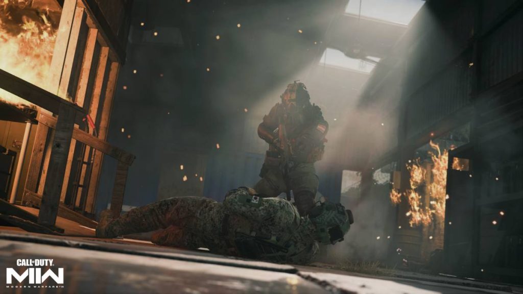 a soldier from MW2 aiming their gun at a soldier lying on the ground while fire rages nearby