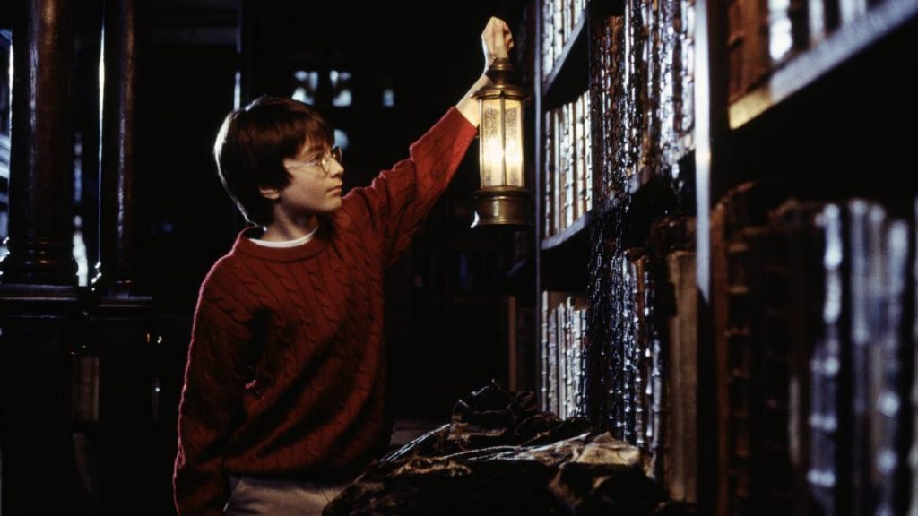 Harry Potter exploring the Restricted Section with a Lamp in the Philosopher's Stone