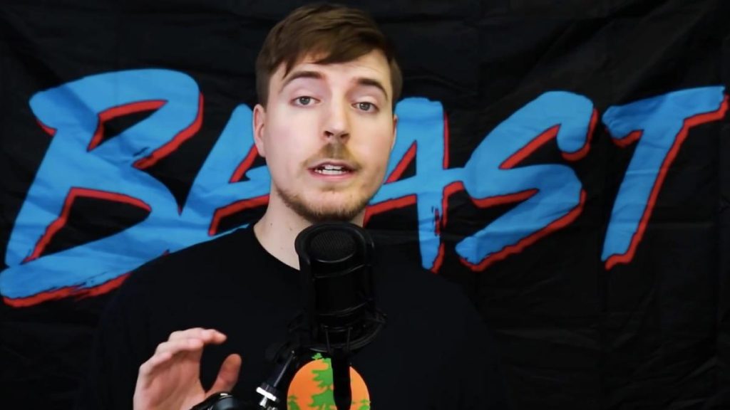 Mr Beast talking into a microphone with his Beast logo behind him